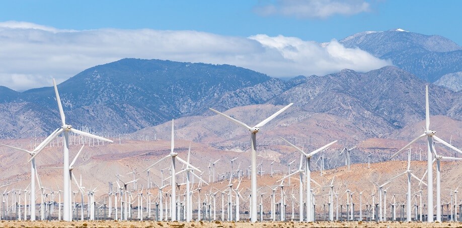a large wind farm and mountains in the background