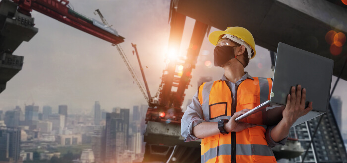 image of a man holding a laptop on a construction site