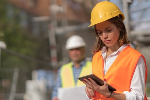 women in yellow hard hat working on a tablet