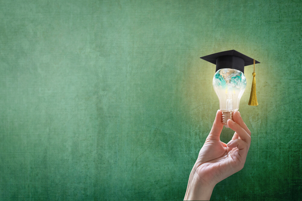 image of a hand holding a lightbulb with a graduation hat on top of it